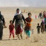 Displaced people from the minority Yazidi sect, fleeing violence from forces loyal to the Islamic State in Sinjar town, walk towards the Syrian border, on the outskirts of Sinjar mountain, near the Syrian border town of Elierbeh of Al-Hasakah Governorate