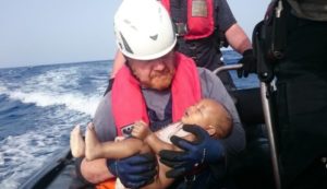 Un voluntario de Sea-Watch sostiene en brazos al bebé tras ser rescatado del mar. 