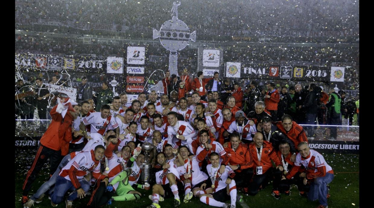 Argentina's River Plate players and staff pose with the trophy, as they celebrate winning the the Copa Libertadores final soccer match against Mexico's Tigres in Buenos Aires, Argentina, Wednesday, Aug. 6, 2015. River defeated Tigres 3-0 and became the tournament champions. (AP Photo/Ivan Fernandez)