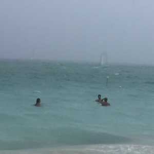 Algunos turistas bañan en las playas de West Bay a pesar del mal tiempo.