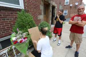 Los vecinos al frente de la residencia de Delman Maldonado preparan un altar. Foto por: Mariela Lombard / El Diario NY