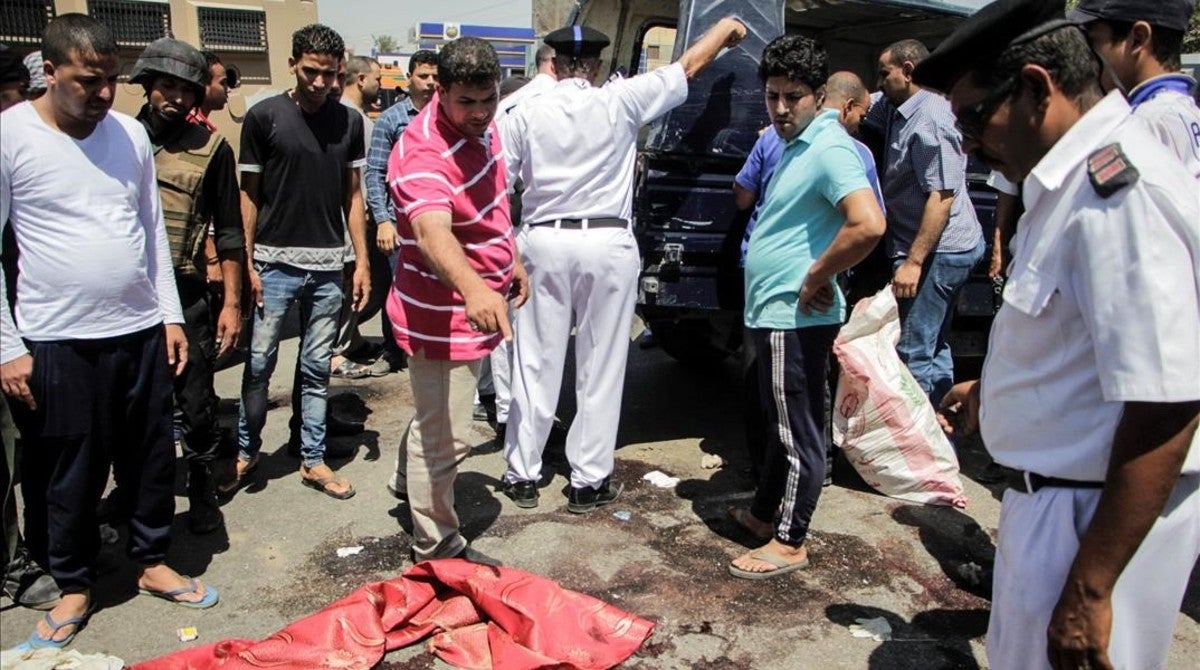 Un grupo de personas inspecciona el lugar donde han sido abatidos a titos cinco policías cerca de la localidad de Badrasheen, a 20 kilómetros de El Cairo.