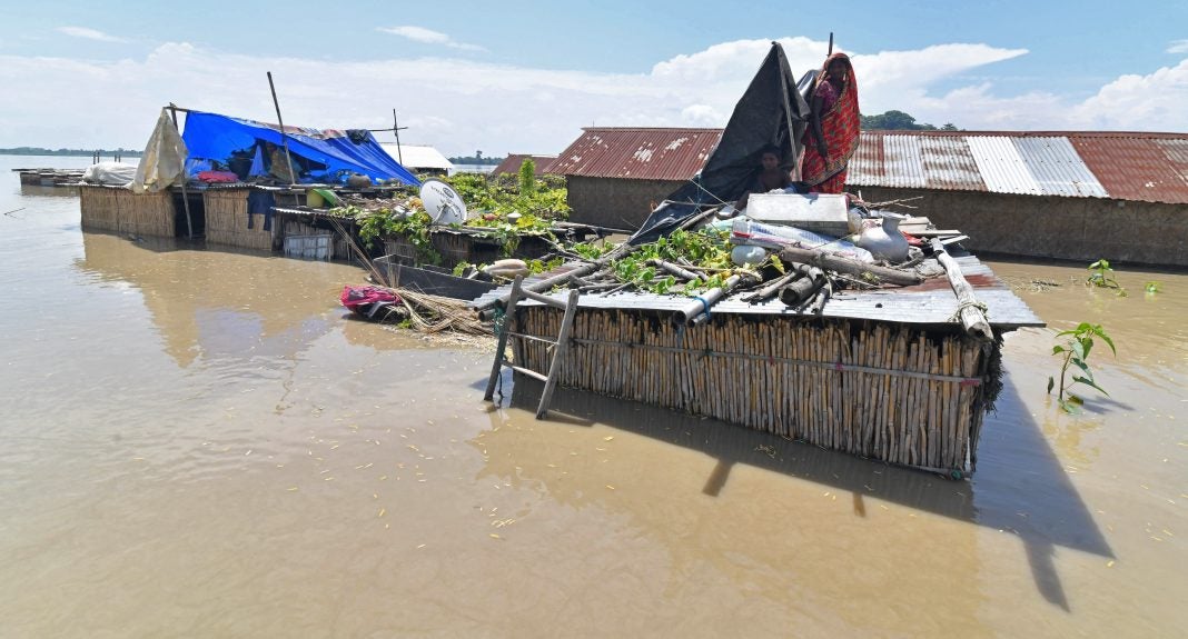 Los aldeanos se refugian en la parte superior de su choza parcialmente sumergida en un área afectada por las inundaciones del distrito de Morigaon en el estado indio de Assam.