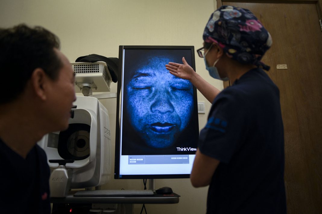Médico examinando una imagen escaneada de un rostro durante una cita para un tratamiento de cuidado de la piel en Beijing.