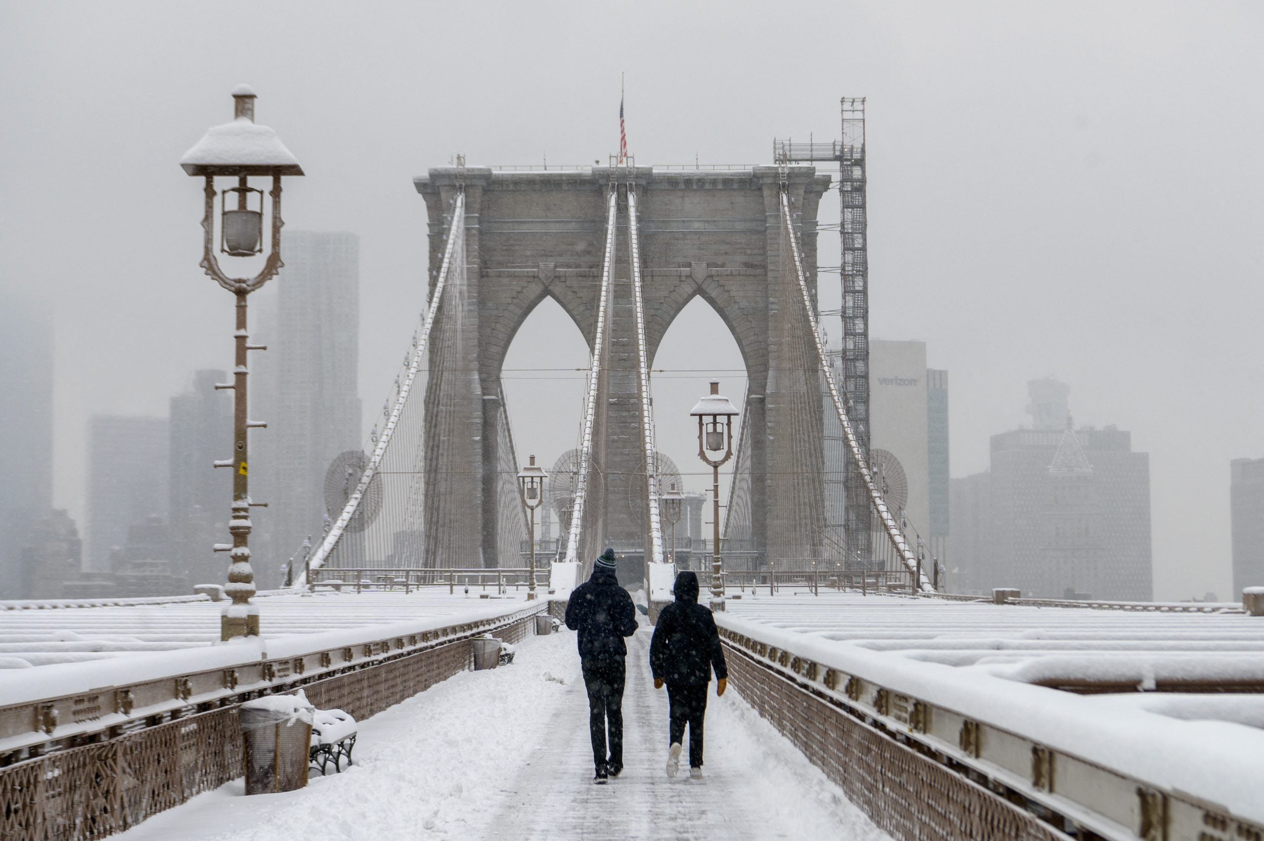 La gente cruza el puente de Brooklyn cubierto de nieve.