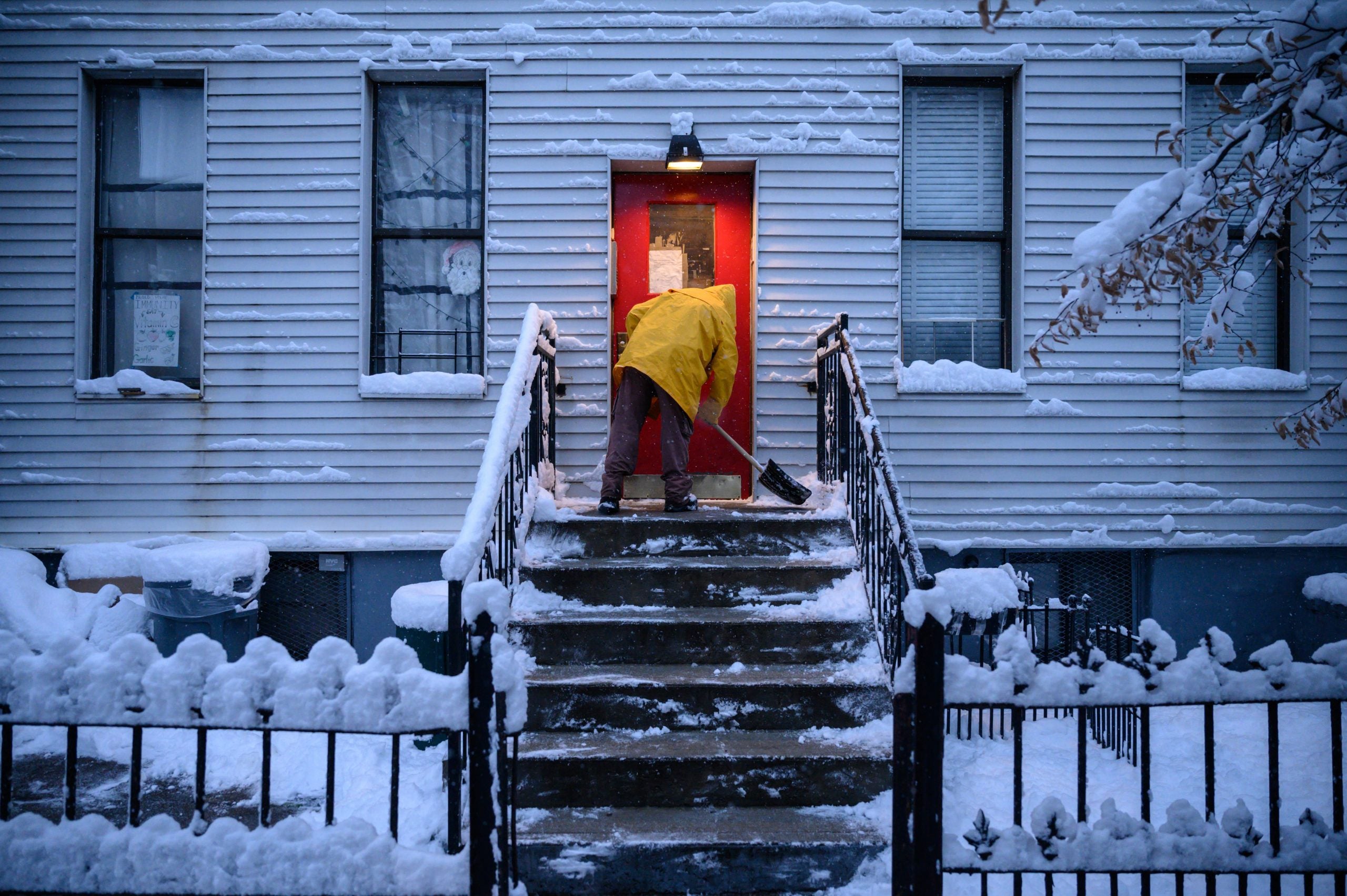 Un hombre quita nieve de una puerta en una calle del distrito de Brooklyn de Nueva York.
