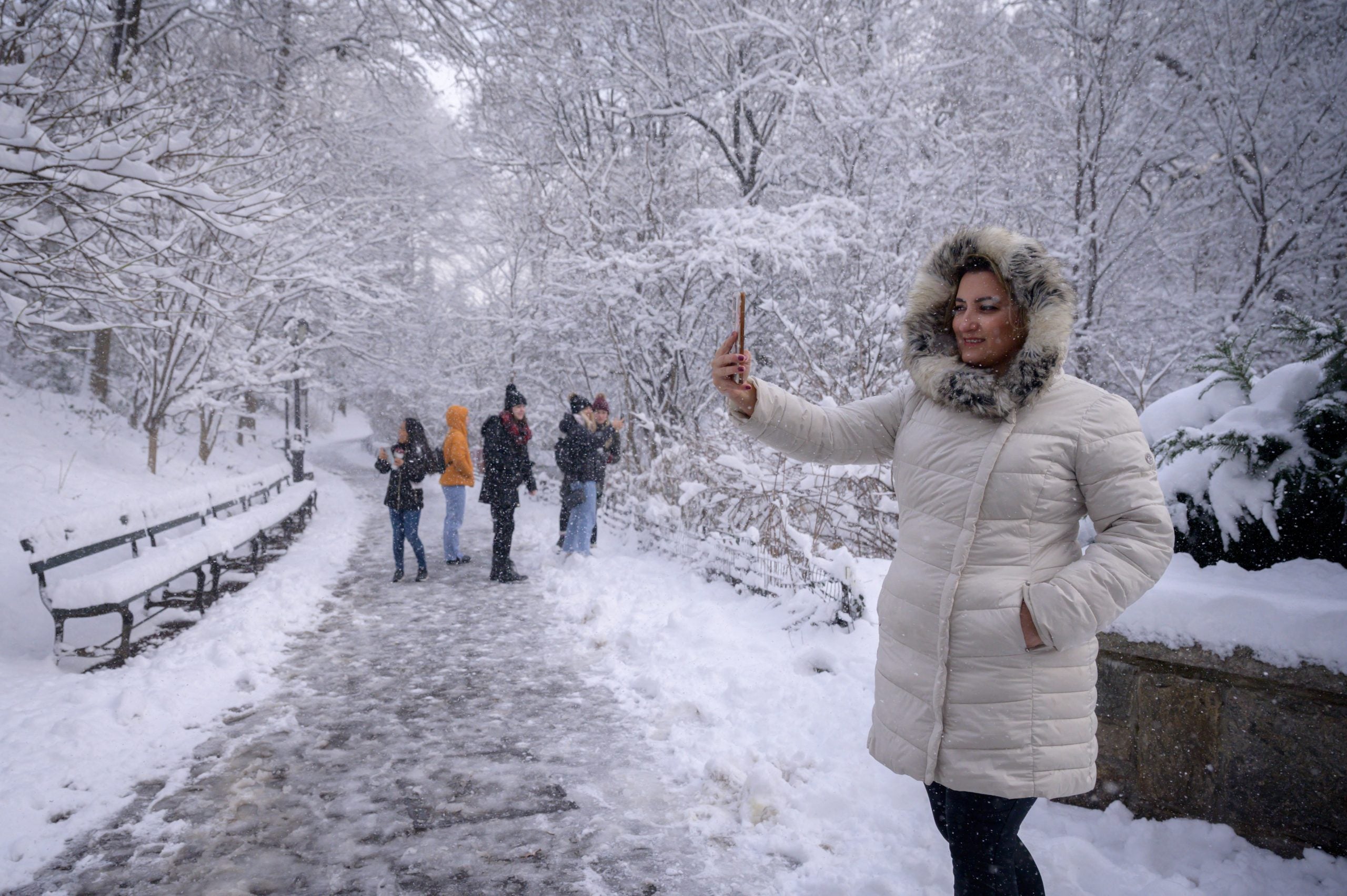 La gente posa para fotos debajo de árboles cubiertos de nieve en Central Park.