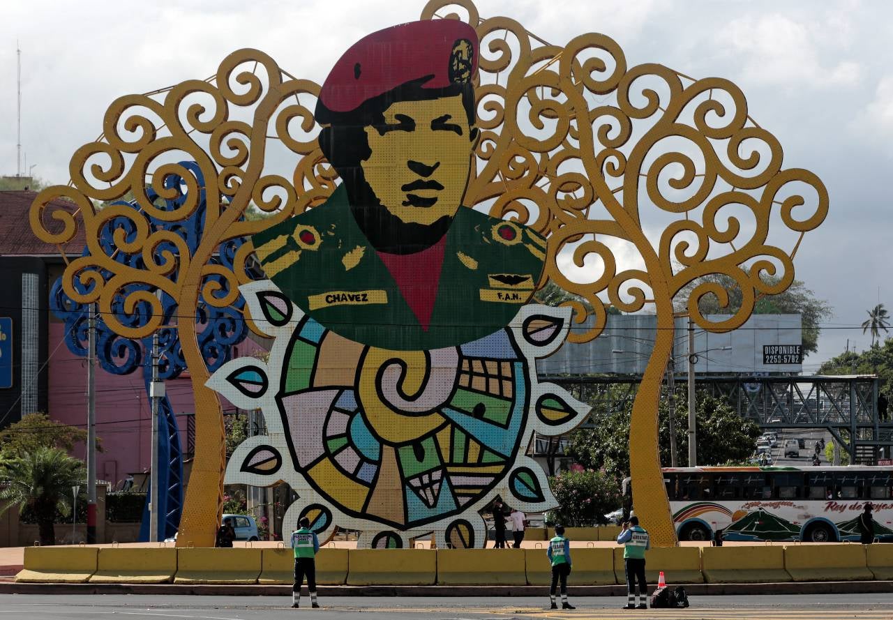Agentes de tránsito se paran frente a un monumento en honor al difunto presidente venezolano, Hugo Chávez, en Managua.