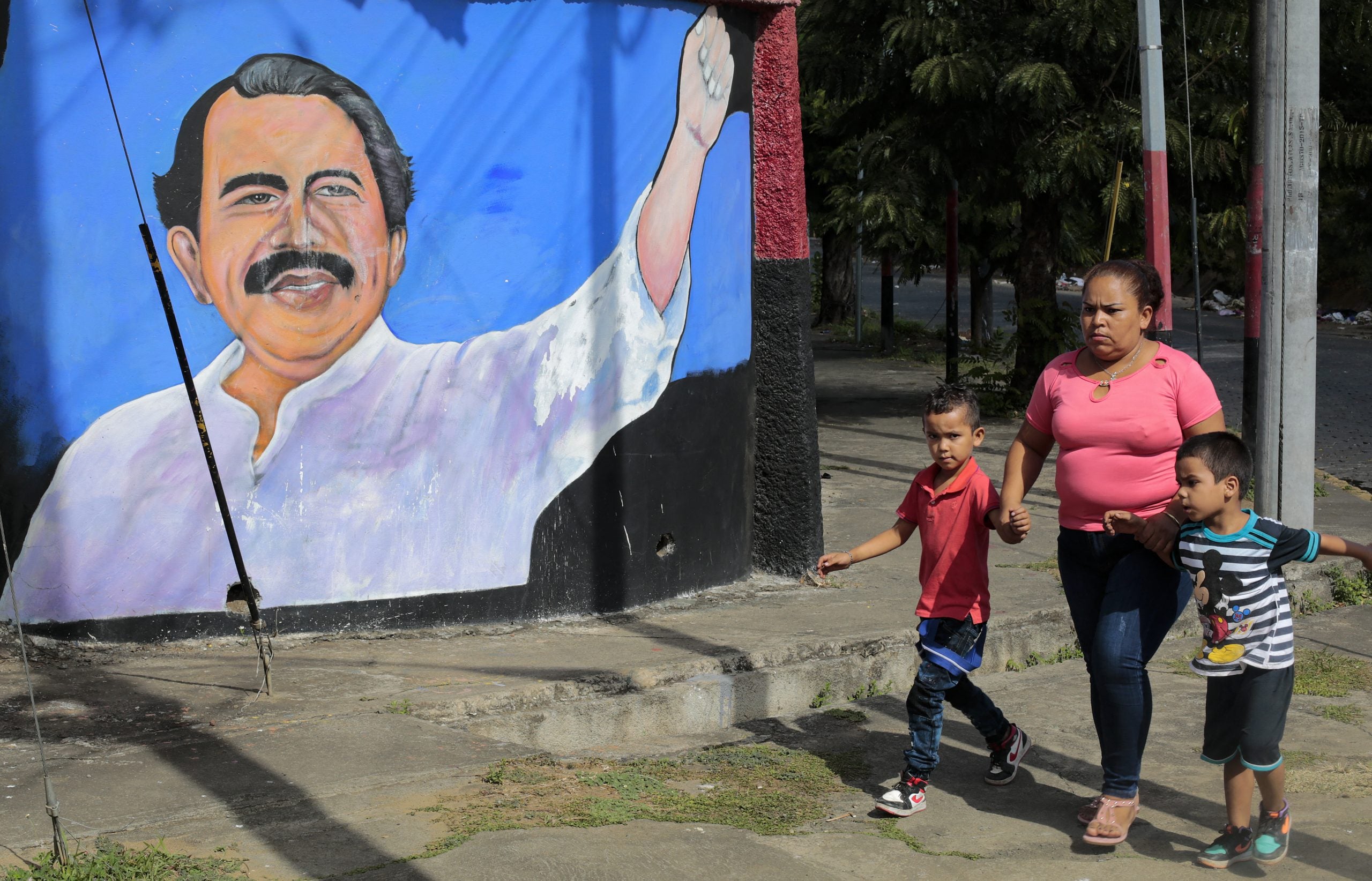 Una mujer y niños caminan junto a un mural que representa al presidente de Nicaragua, Daniel Ortega, en Managua el 10 de enero de 2022.