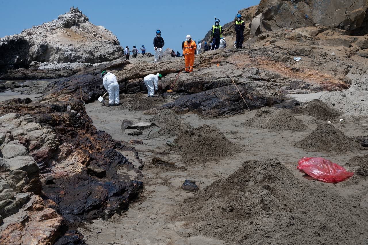 Equipos de limpieza trabajan para retirar petróleo de una playa en la provincia peruana del Callao.
