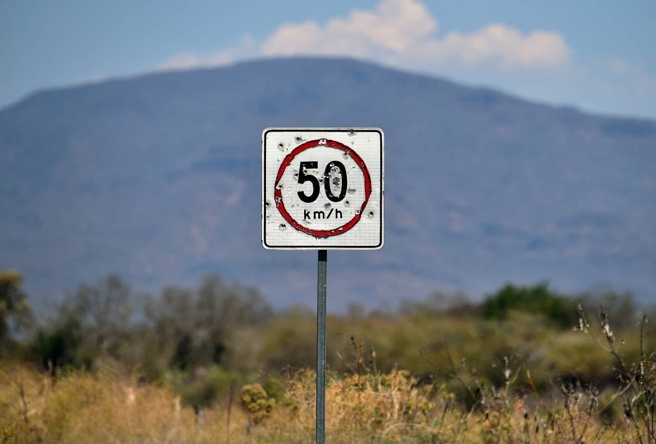 Señal de límite de velocidad con orificios de bala en la carretera Buenavista Tomatlán, Aguililla.