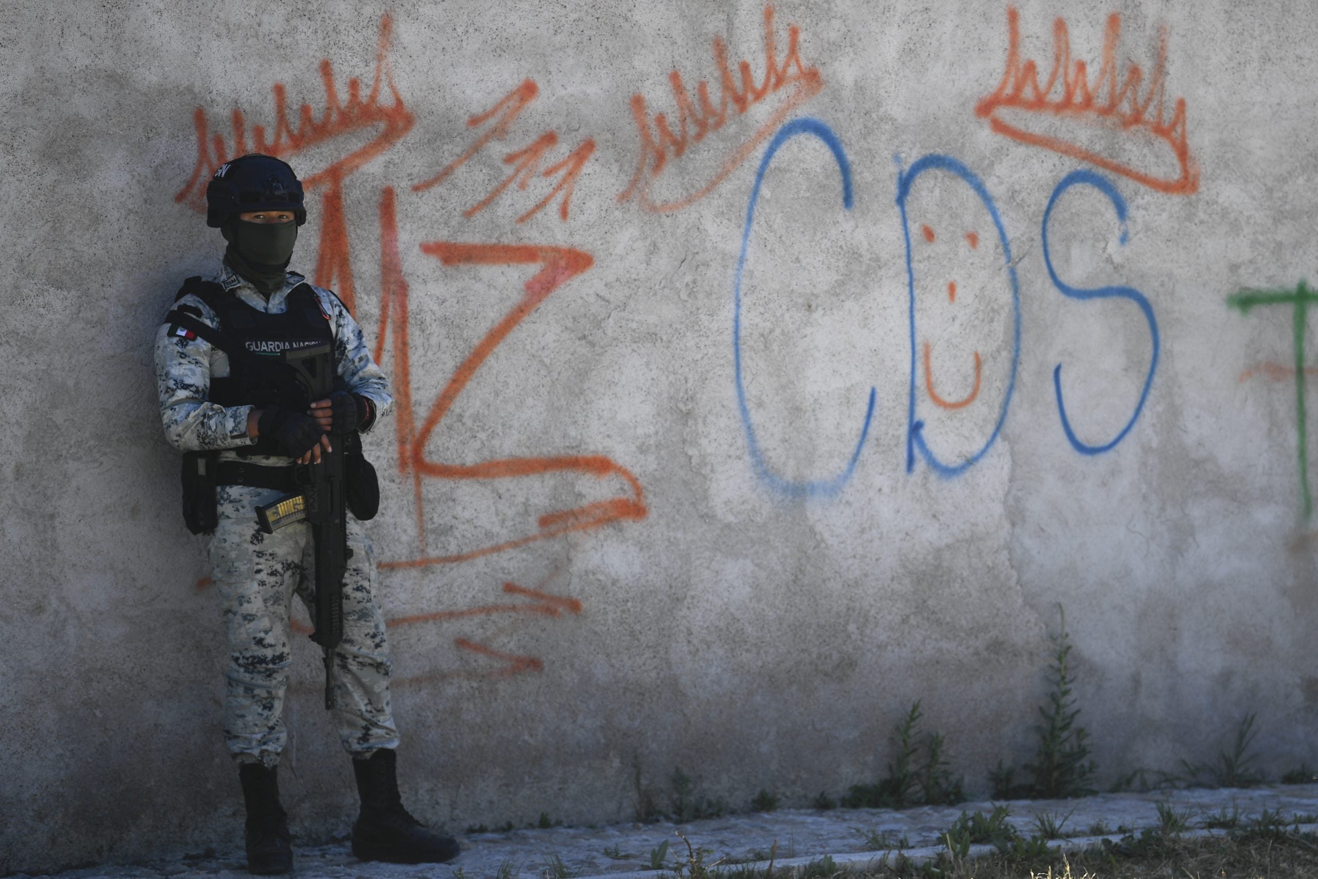 Un guardia junto a unos grafitis del narcotraficante Mayo Zambada (MZ) y el grupo criminal "Cartel de Sinaloa" (CDS), en la vereda Palmas Altas.