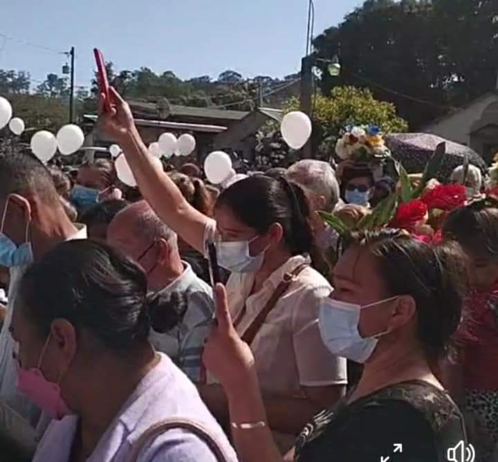 Personas con globos dándole el último adiós al sacerdote.