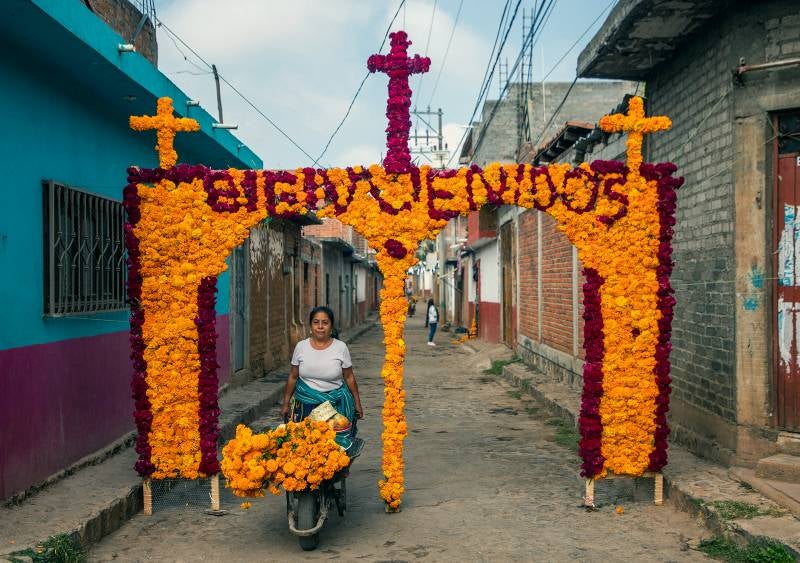 Un familiar de María Salud Ramírez Caballero, conocida como Mamá Coco, decora un arco con flores en la calle donde vivía para recibir la visita de turistas.