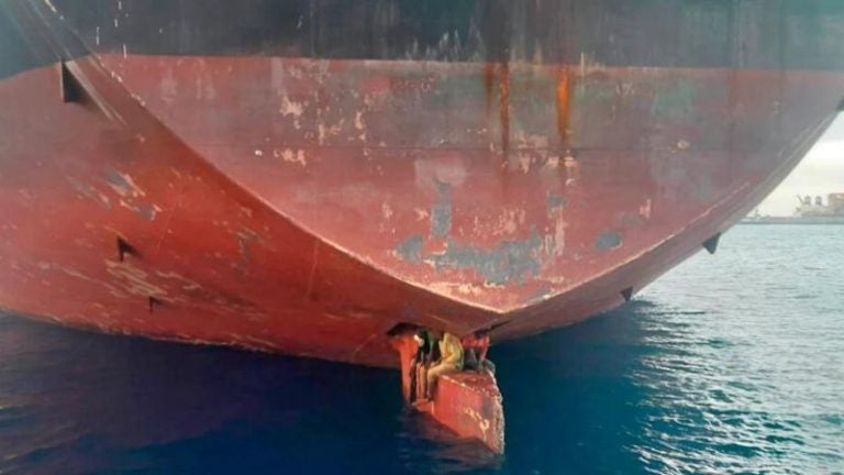 Migrantes cruzan el mar sentados en el timón de un barco petrolero