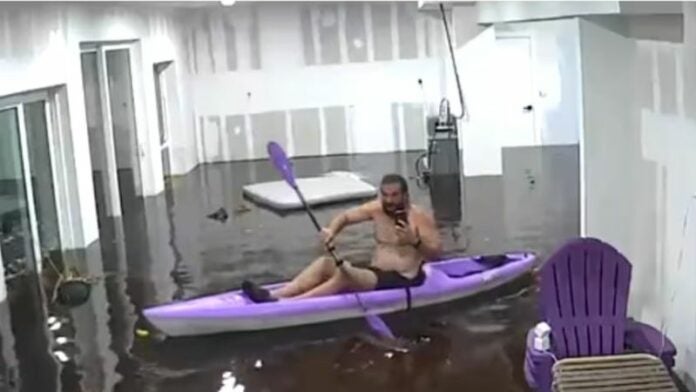 Hombre se sube en un kayak en su casa inundada por el huracán Helene