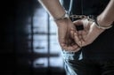 arrested-man-in-handcuffs-with-handcuffed-hands-behind-back-in-prison
