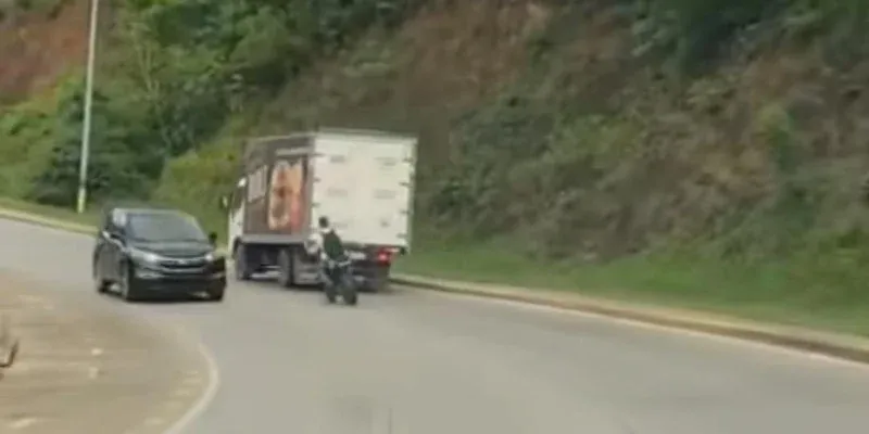 Motociclista desafía la muerte en curva de Dixon Cove al rebasar a camión