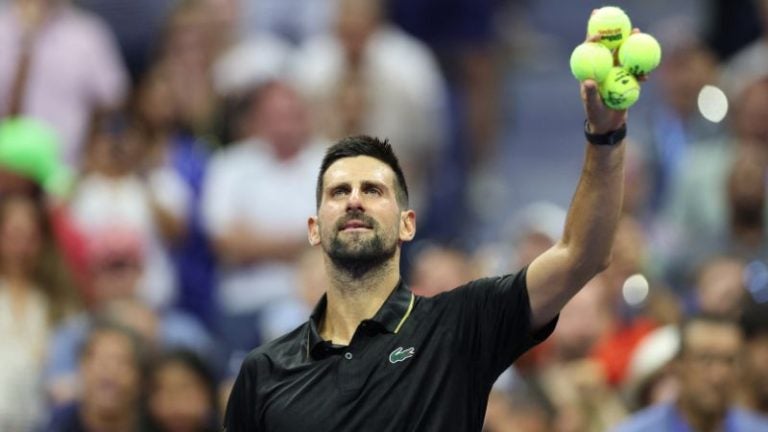 El serbio Novak Djokovic se prepara para lanzar pelotas de tenis autografiadas a los aficionados tras ganar su partido de primera ronda individual masculino contra el estadounidense Learner Tien.
