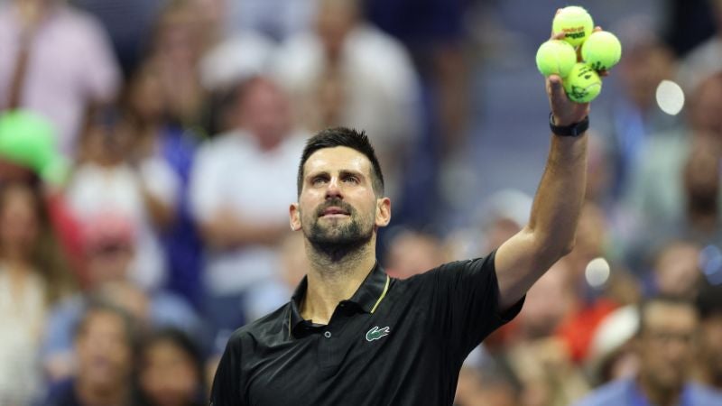 El serbio Novak Djokovic se prepara para lanzar pelotas de tenis autografiadas a los aficionados tras ganar su partido de primera ronda individual masculino contra el estadounidense Learner Tien.